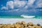 Turquoise rolling wave slamming on the rocks of the coastline