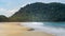 Turquoise sea and gold fine sand surrender by a mountain with many green trees. Empty Sin Htauk Beach in Myanmar