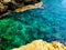 Turquoise sea water with grey natural stones. Purity ripple ocean water surface with selective focus and sun light. Transparent