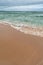 Turquoise sea with waves and sea foam, sandy beach