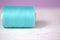 Turquoise thread on a lilac and white background