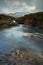 Turquoise and transparent water with rocks and silky water. red cliff and wintes mountains - Fairy Pools - Skye Island - Scotland