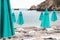 Turquoise umbrellas, white sunbeds, beach, sea.The end of the summer season. Closed turquoise umbrellas and white sunbeds on the