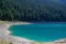 Turquoise water of the lake, pine forest and mountains. Stunning background with nature