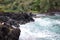 Turquoise water rushing into a black lava rocky cove at Wailua Lookout in Haiku, Maui