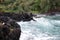 Turquoise water rushing into a black lava rocky cove at Wailua Lookout in Haiku, Maui, Hawaii