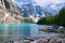 Turquoise waters of beautiful Moraine lake. Snow-covered Rocky mountains in summer day. Canoes on a jetty.