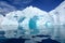 Turquoise and white iceberg with bows and caves, dark blue sea ice flows and reflections, Paradise Bay, Antarctica