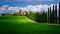 Tuscany famous cypress trees with farmer house on a sunny day and white clouds