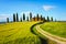 Tuscany, farmland, cypress trees and white road on sunset. Siena, Italy.