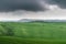 Tuscany, rural landscape. Countryside farm, cypresses trees, green field, cloudy day