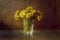 Tussilago bouquet in glass in water drops and sunshine