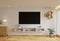 TV in the living room on a white wall by the window, decorated with plants, vases, flowers, toys and lamps.3d rendering