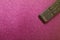 Tv remote in on a pink glitter glamor background. Cinema, entertainment, TV concept