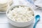 Tvorog, farmers cheese, curd cheese or cottage cheese in white bowl on white wooden table