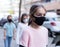 Tween girl in black mask walking along city street