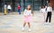 Tween girl in pink skirt jumping rope in schoolyard during recess