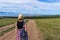 Tween tourist girl in hat and backpack walking on country road alone and admiring picturesque landscape of lake Baikal, mountains