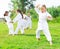 Tweenager girl mastering karate moves with group on green lawn