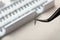 Tweezers with bunch of artificial eyelashes on blurred background, closeup.