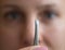 Tweezers with gray hair in front of the woman face
