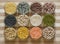 Twelve bowls of lentils and legumes on a chopping board