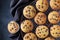 Twelve freshly baked choco chip muffins cooling off on wire mesh on dark background, flat layout