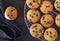 Twelve freshly baked choco chip muffins cooling off on wire mesh on dark background with linen towel