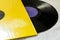 Twelve inch vinyl black record in yellow sleeve