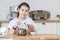 Twelve years old girl holding teapot with opened cap in hands, looking at camera, kitchen interior