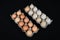 Twenty chicken eggs in two carton boxes, isolated on black mat background