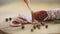 Twig of fresh rosemary and seeds of pepper lying on scratched board near delicious sliced and whole sausages