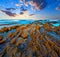 Twilight ocean coast with ribbed stratiform rock