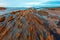 Twilight ocean coast with ribbed stratiform rock.