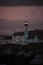 Twilight Sentinel: Serene Lighthouse Silhouetted Against the Coastal Sunset, Guiding Ships with Majestic Charm. ai generative