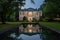 twilight view of a greek revival home with a reflective pond