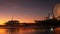 Twilight waves against classic illuminated ferris wheel, amusement park on pier in Santa Monica pacific ocean beach resort.