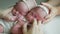 Twin babies sleep in the crib in dresses