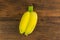 Twin bananas on wood background.