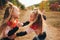 Twin blondes walk and have fun in the autumn forest among the red trees.