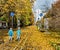 Twin boys in the park under falling maple leaves.