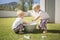 Twin Boys Wash Their Hands in a Foamy Bucket on a Grassy Lawn