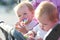 Twin children sit in a baby carriage with toys