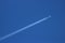 Twin engined jet plane with contrail in blue sky