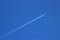 Twin engined jet plane with contrail in blue sky