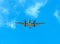 Twin propeller aircraft flying in a blue sky