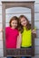 Twin sister girls posing with aged wooden border frame