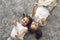 Twin sisters child showing thumbs up gesture while lying on soft carpet, top view. Joyful siblings spending time