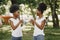 Twin sisters holding a cups with drinks and looking on each other