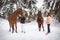 Twin sisters and horse in the winter forest